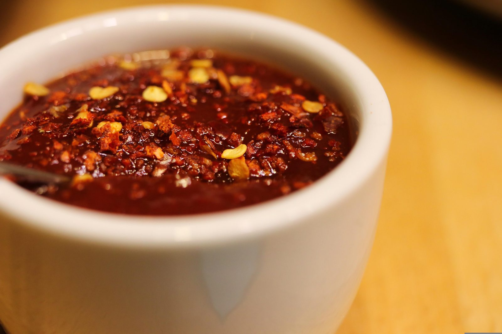 A bowl of fiery red dalle khursani momo dip topped with chilli flakes